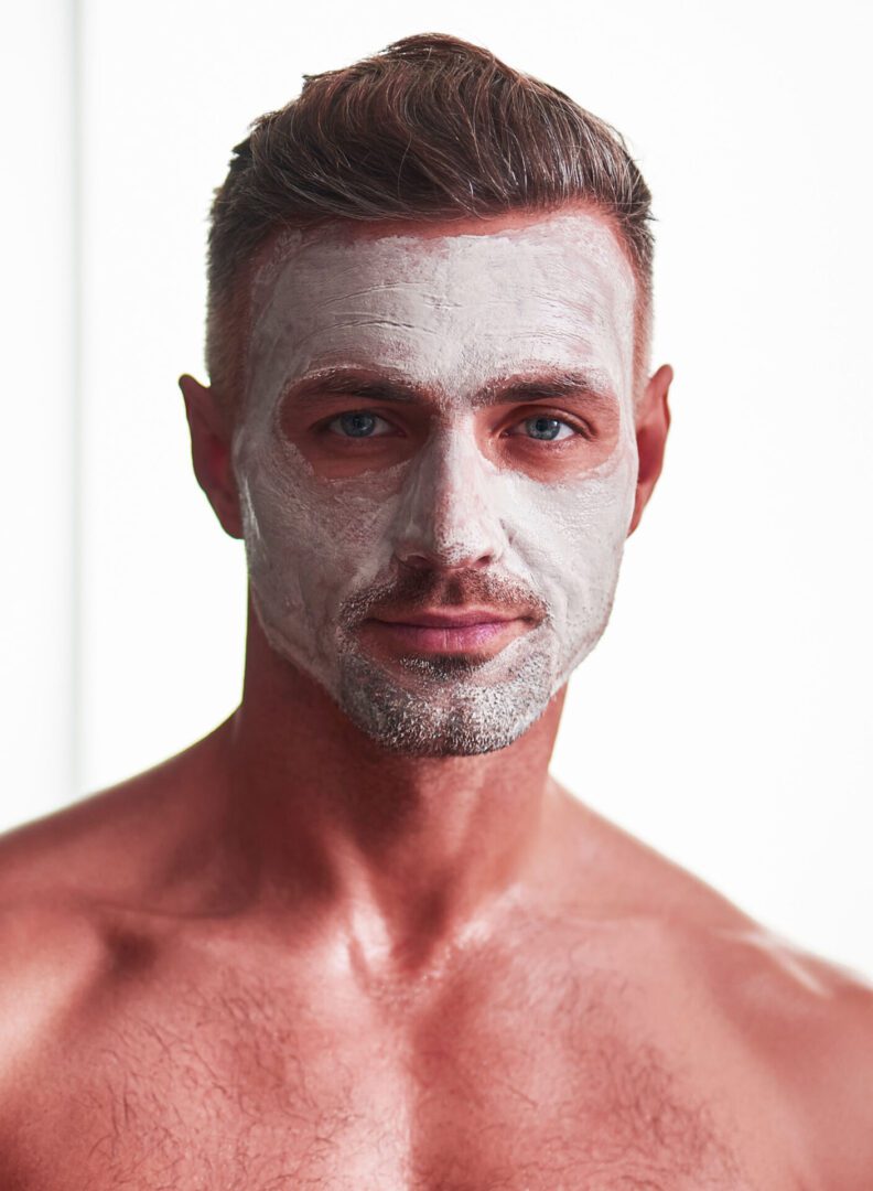 Waist up portrait of attractive muscular gentleman having skincare cosmetic procedure. He is looking at camera with slight smile