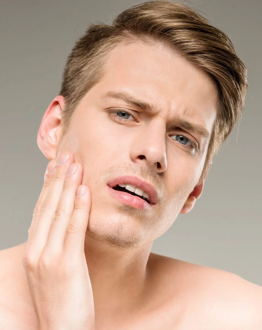 Handsome man with pure skin touching his face.